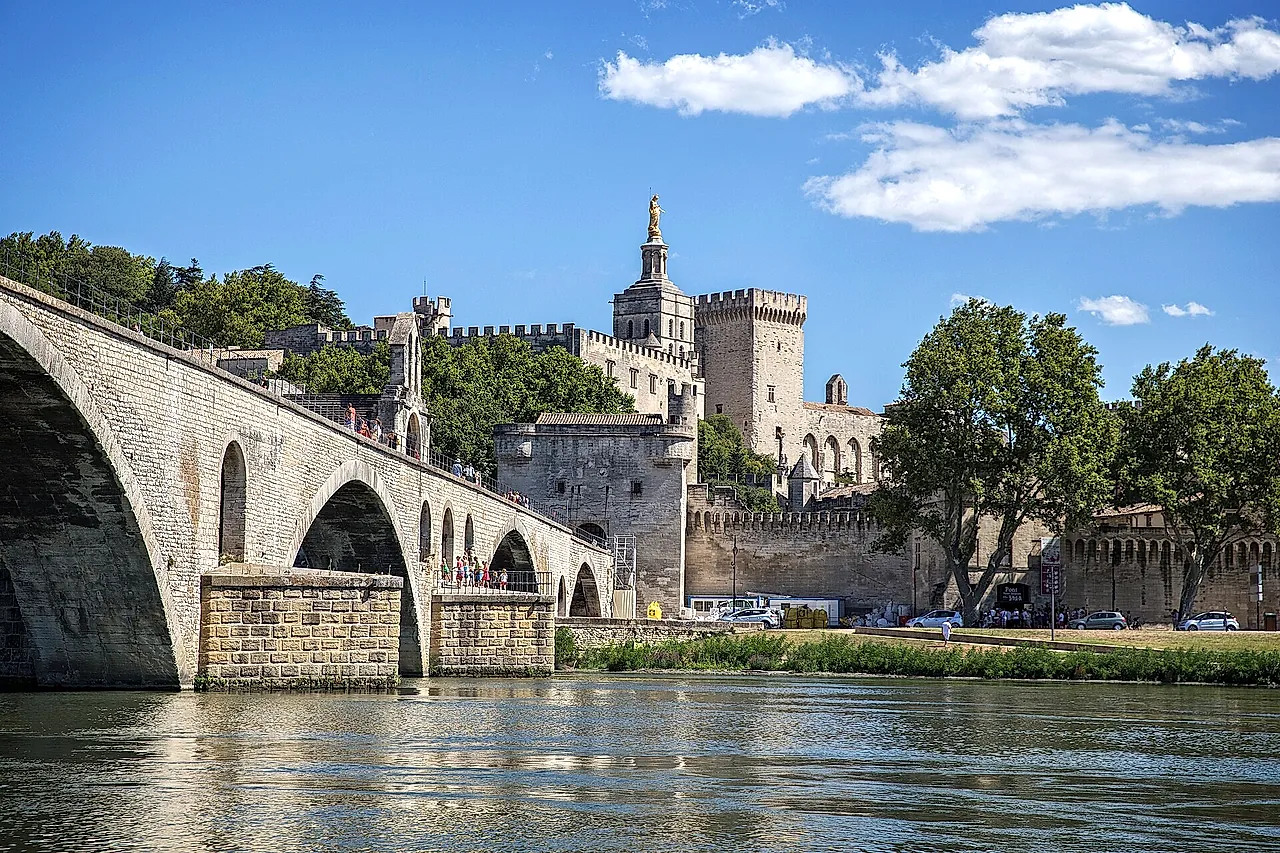 Los arcos del Puente de Aviñón (Pont Saint-Bénézet) sobre el Ródano, con las torres del Palacio de los Papas y la estatua dorada de la catedral detrás de las murallas
