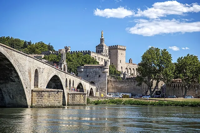 Le arcate del Pont Saint-Bénézet sul Rodano, con le torri del Palais des Papes e la statua dorata della cattedrale dietro le mura