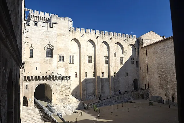 La Cour d'honneur del Palais des Papes, con le alte mura merlate e le arcate a sesto acuto al sole