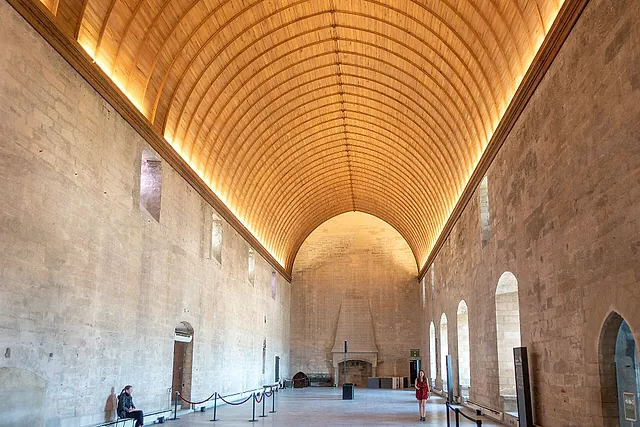 Il Grand Tinel del Palais des Papes, una lunga sala sotto una volta a botte in legno illuminata, con un camino in fondo