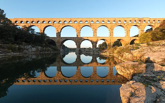 Il Pont du Gard nella luce calda della sera, con le file di arcate riflesse nel fiume