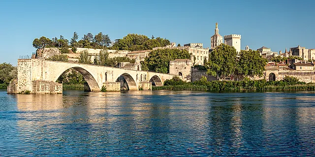 Le arcate del Pont d'Avignon sopra il Rodano nella luce dorata, con il Palais des Papes e la cattedrale sulla collina dietro